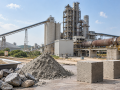 Cement strength testing materials with cement powder, aggregates, concrete test cubes, and a cement manufacturing plant in the background
